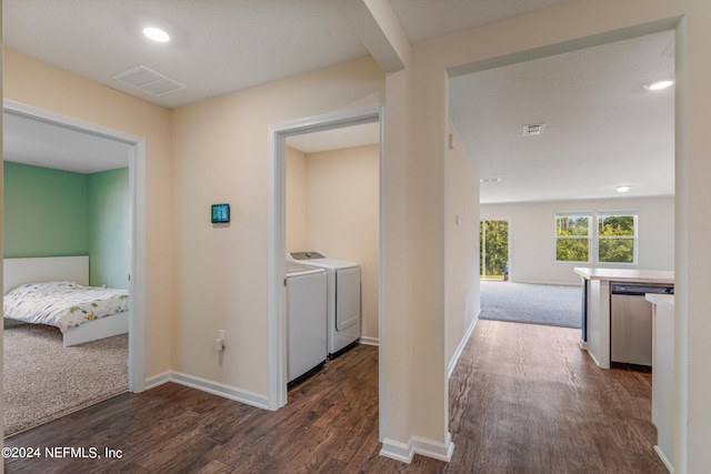 corridor with visible vents, independent washer and dryer, and wood finished floors