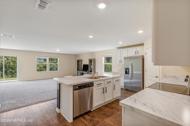 kitchen with visible vents, open floor plan, white cabinets, stainless steel appliances, and a sink