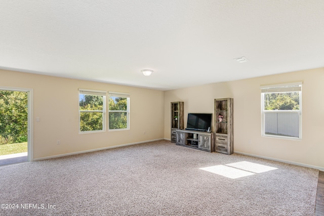 unfurnished living room featuring visible vents, baseboards, and carpet