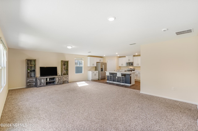 unfurnished living room with recessed lighting, visible vents, baseboards, and dark carpet