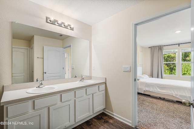 full bathroom featuring double vanity, connected bathroom, a textured ceiling, and a sink