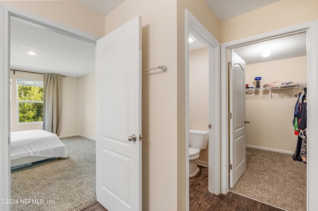 hall featuring baseboards and dark carpet