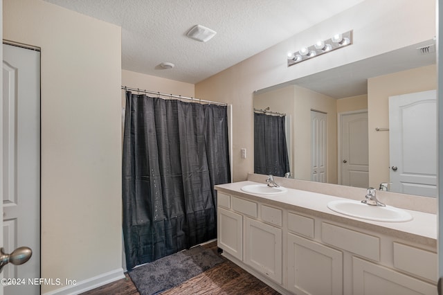 bathroom featuring double vanity, visible vents, a textured ceiling, and a sink