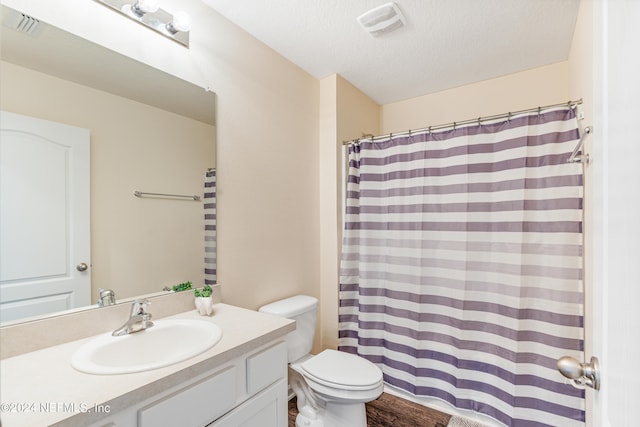 full bathroom with vanity, toilet, visible vents, and a textured ceiling