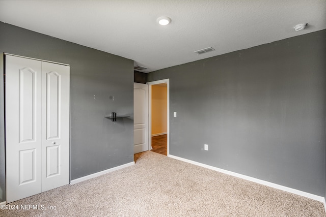 unfurnished bedroom with visible vents, a closet, carpet floors, and baseboards