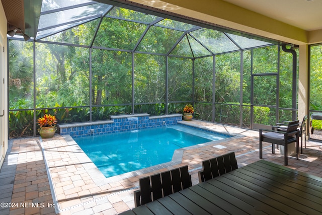 view of pool with glass enclosure, a patio area, and pool water feature