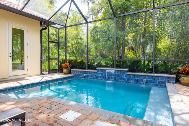 view of swimming pool with glass enclosure, pool water feature, and a patio