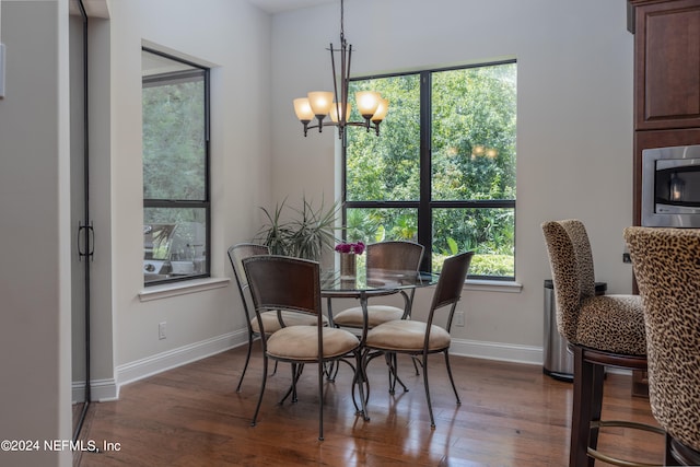 dining area featuring a fireplace, dark wood-type flooring, and an inviting chandelier