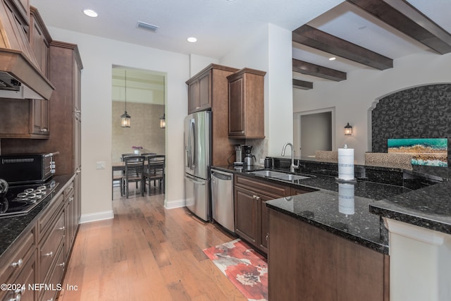 kitchen with dark stone counters, stainless steel appliances, light hardwood / wood-style flooring, and sink