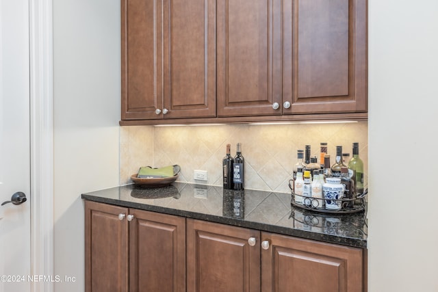 bar featuring dark stone countertops and backsplash