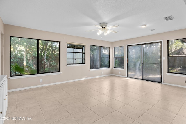 tiled empty room with ceiling fan and a textured ceiling