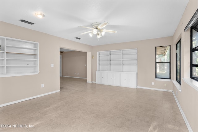 unfurnished room featuring built in shelves, ceiling fan, and light tile patterned flooring