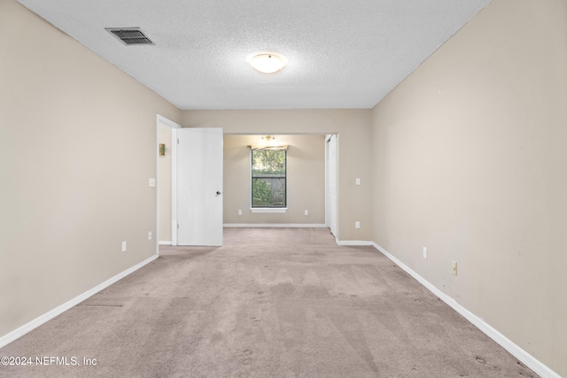 carpeted empty room featuring a textured ceiling