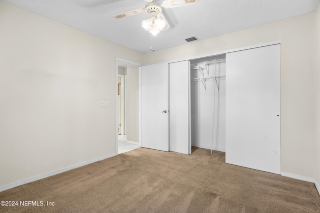 unfurnished bedroom with carpet, ceiling fan, a textured ceiling, and a closet