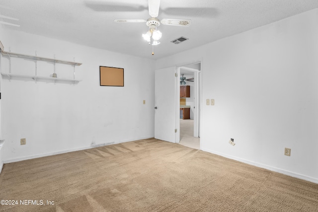 carpeted spare room featuring ceiling fan and a textured ceiling