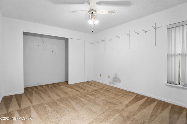 unfurnished bedroom with ceiling fan, a closet, carpet floors, and a textured ceiling