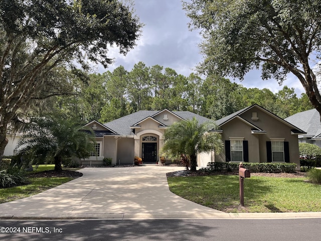 single story home featuring driveway, a front yard, and stucco siding