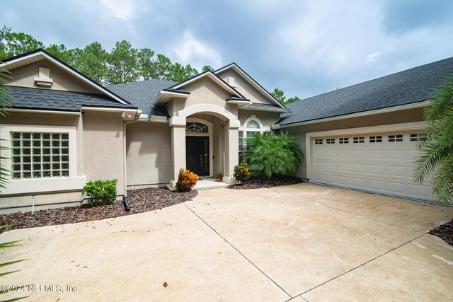 single story home with a shingled roof, driveway, and stucco siding