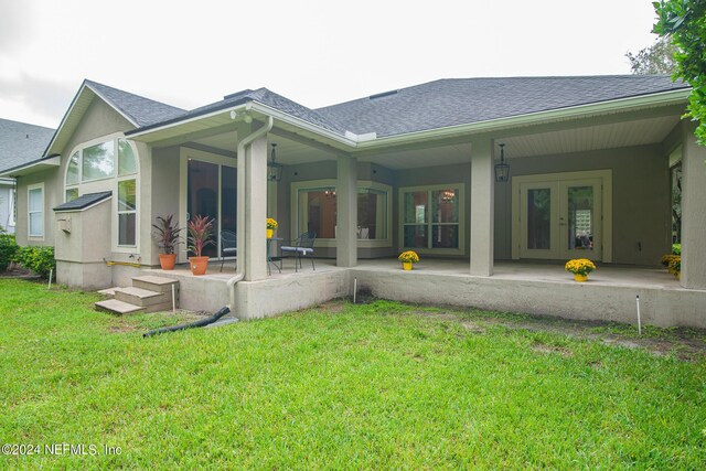 rear view of property featuring french doors, roof with shingles, and a lawn