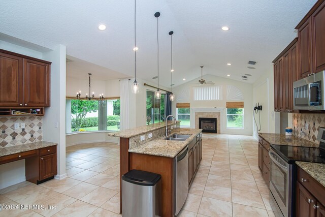 kitchen with a fireplace, stainless steel appliances, lofted ceiling, open floor plan, and a sink