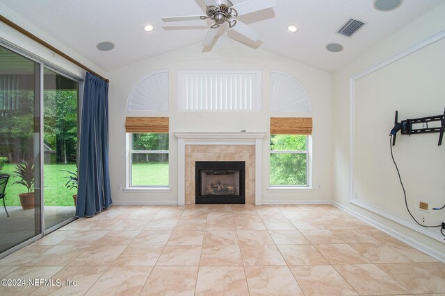 unfurnished living room with a tile fireplace, a healthy amount of sunlight, visible vents, and vaulted ceiling