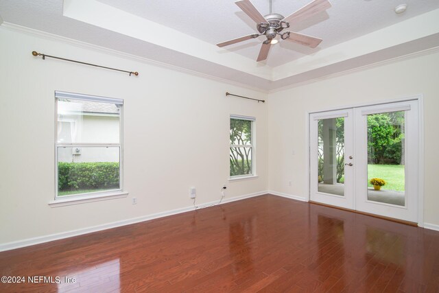 unfurnished room featuring baseboards, ceiling fan, wood finished floors, a tray ceiling, and french doors