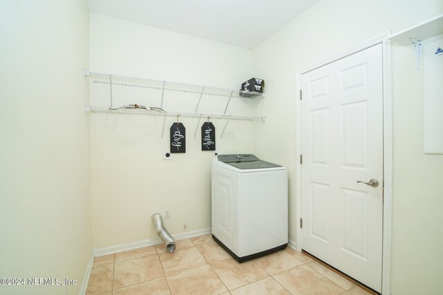 laundry area featuring washer / clothes dryer, light tile patterned flooring, baseboards, and laundry area