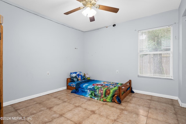 tiled bedroom featuring multiple windows and ceiling fan