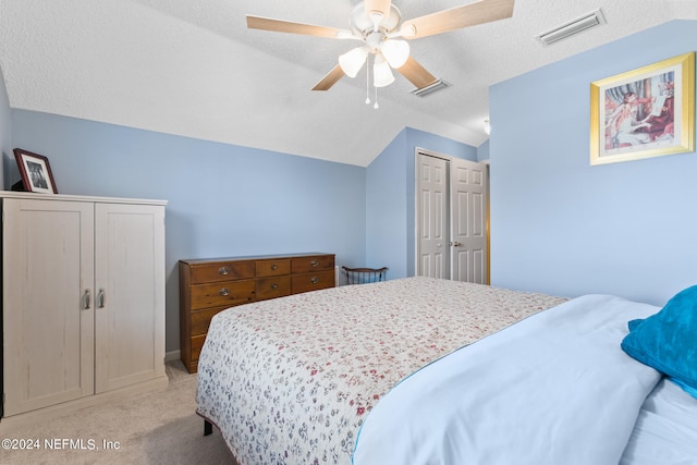 bedroom featuring light carpet, a textured ceiling, vaulted ceiling, and ceiling fan