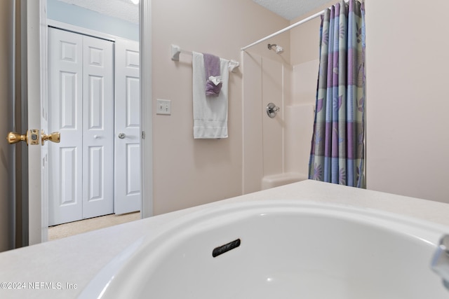 bathroom with a textured ceiling and a shower with curtain