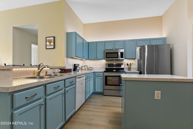 kitchen featuring appliances with stainless steel finishes, light hardwood / wood-style flooring, blue cabinets, and sink