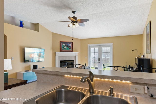 kitchen featuring sink, a textured ceiling, lofted ceiling, and a fireplace