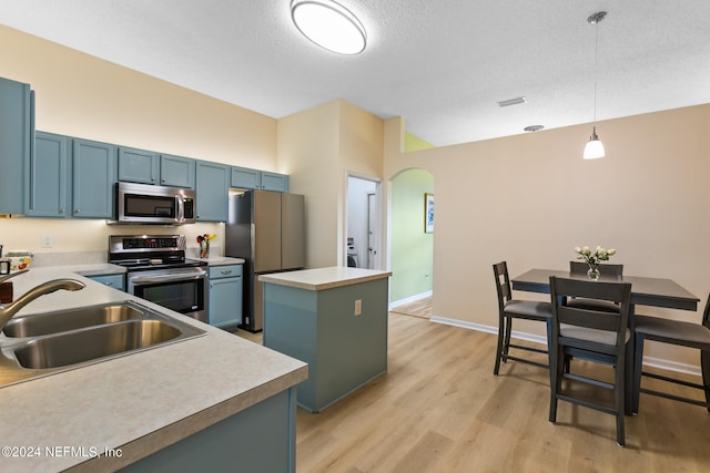 kitchen featuring a kitchen island, hanging light fixtures, sink, appliances with stainless steel finishes, and light hardwood / wood-style floors