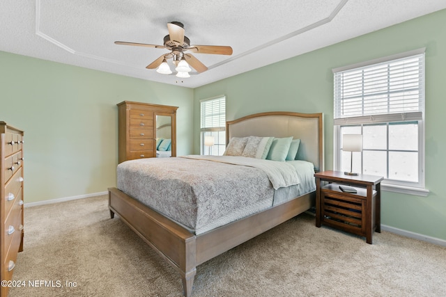 bedroom with light carpet, multiple windows, a textured ceiling, and ceiling fan