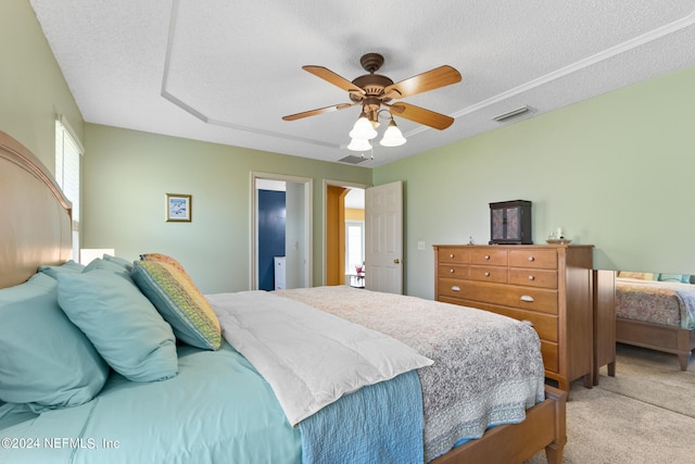 bedroom featuring light carpet, a textured ceiling, and ceiling fan