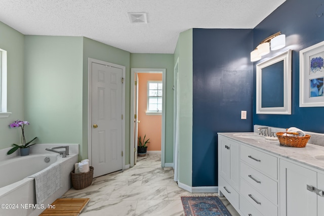 bathroom featuring vanity, a bathtub, and a textured ceiling