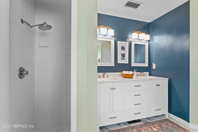 bathroom featuring vanity, a textured ceiling, hardwood / wood-style flooring, and tiled shower