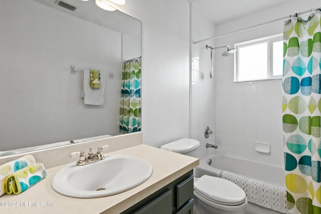 full bathroom with vanity, toilet, shower / bath combo with shower curtain, and a textured ceiling