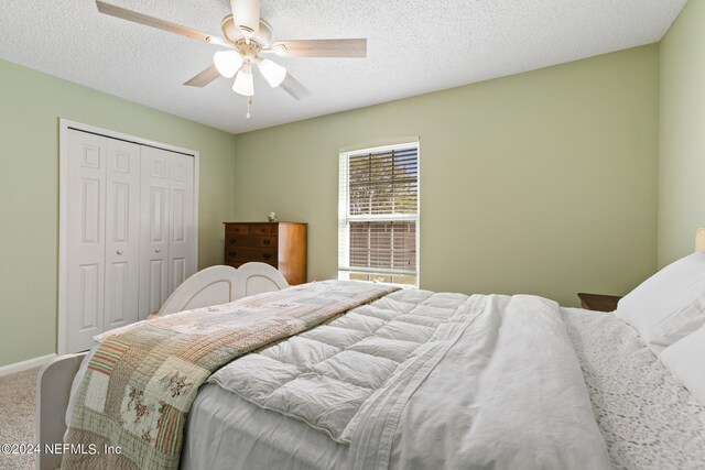 bedroom with a closet, ceiling fan, a textured ceiling, and carpet floors