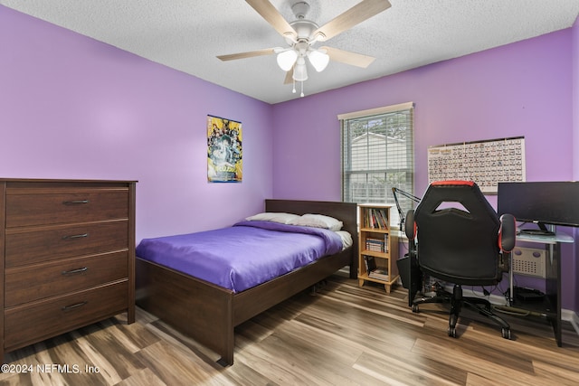 bedroom featuring ceiling fan, wood-type flooring, and a textured ceiling