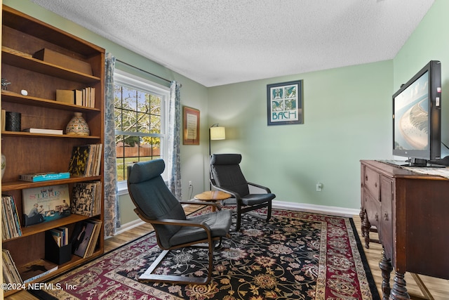 sitting room featuring a textured ceiling and light wood-type flooring