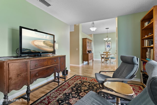 sitting room with light hardwood / wood-style flooring, a textured ceiling, and a notable chandelier