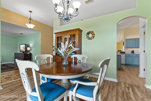 dining area with an inviting chandelier and light hardwood / wood-style flooring