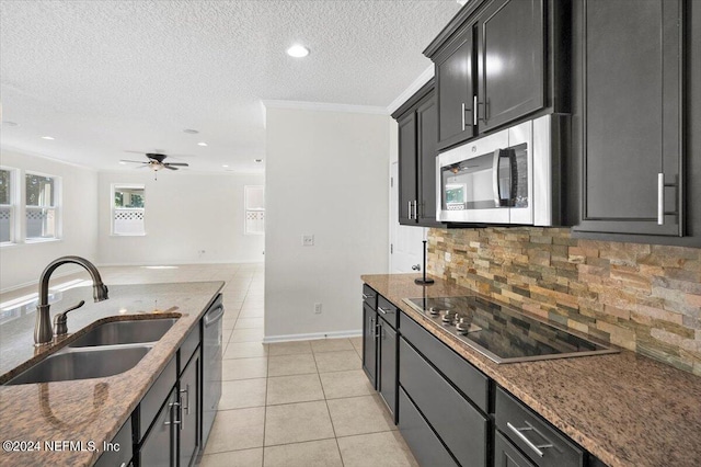 kitchen with light tile patterned floors, stainless steel appliances, a sink, dark stone counters, and dark cabinetry