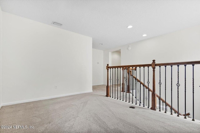 empty room featuring carpet, recessed lighting, visible vents, a textured ceiling, and baseboards