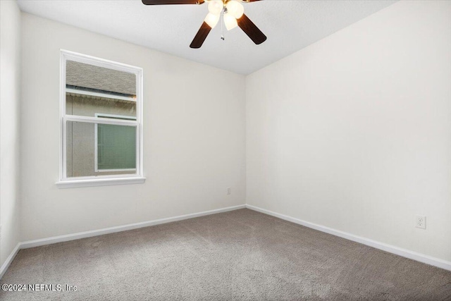 carpeted spare room featuring ceiling fan and baseboards