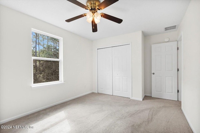 unfurnished bedroom featuring carpet floors, a ceiling fan, visible vents, baseboards, and a closet