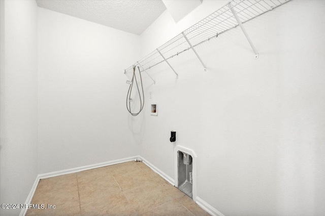 laundry area featuring laundry area, baseboards, tile patterned floors, a textured ceiling, and washer hookup