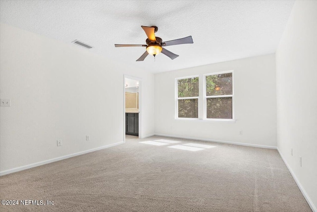 spare room with a textured ceiling, baseboards, and light colored carpet