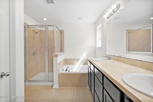 full bath featuring a garden tub, a stall shower, a sink, a textured ceiling, and tile patterned flooring